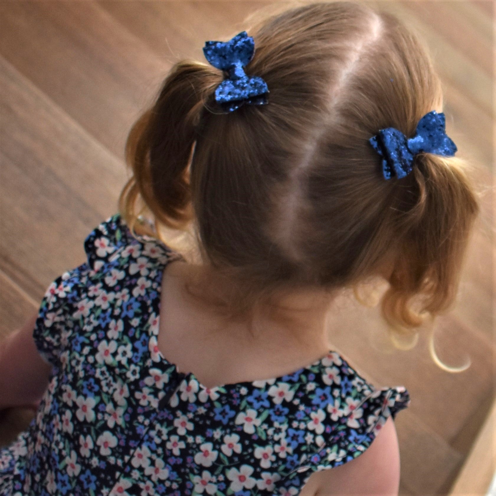 A child with navy blue glittery piggytail bows in her hair.