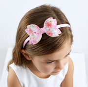 Young girl wearing a pink floral bow headband